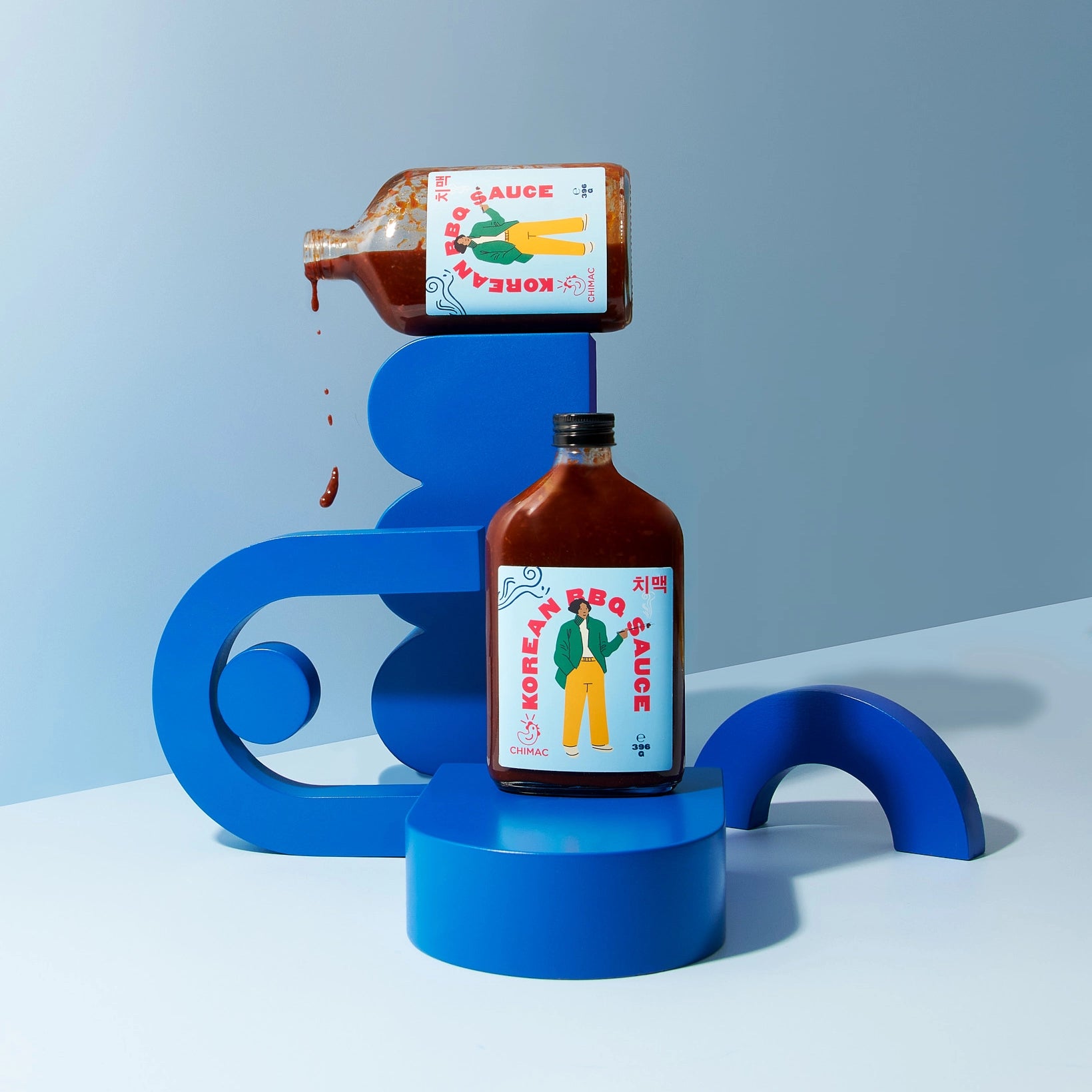 Bottle of Korean BBQ sauce on a blue platform with a blue background